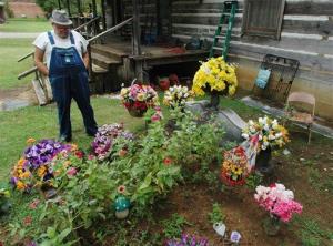 In this Friday, Aug. 10, 2012, photo, James Davis, 73, stands over the grave of his wife, Patsy, in the front yard of the home they shared in Stevenson, Ala.