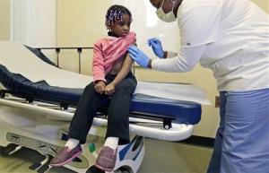Four-year-old Gabriella Diaz sits as registered nurse Charlene Luxcin, right, administers a flu shot at the Whittier Street Health Center in Boston, Mass., Wednesday.