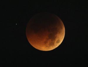 The moon exhibits a deep orange glow in a total lunar eclipse as seen in 2011.